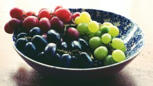 A vibrant bowl of fresh red, green, and black grapes, showcasing healthy eating.