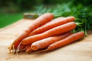 BALANCE YOUR MIND WITH AYURVEDA A bunch of fresh organic carrots on a wooden surface, perfect for healthy cooking.