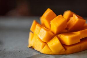 Close-up of juicy sliced mango cubes on a gray surface, perfect for summer refreshment.