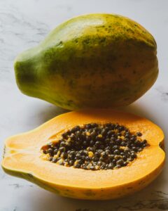 Close-up of ripe papaya cut open on a marble surface, showcasing juicy seeds.