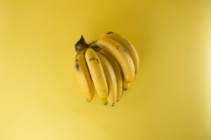 A vibrant bunch of ripe bananas on a matching yellow background, evoking freshness.