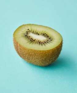 Close-up of a fresh kiwi half on a blue background, highlighting its vibrant colors and textures.
